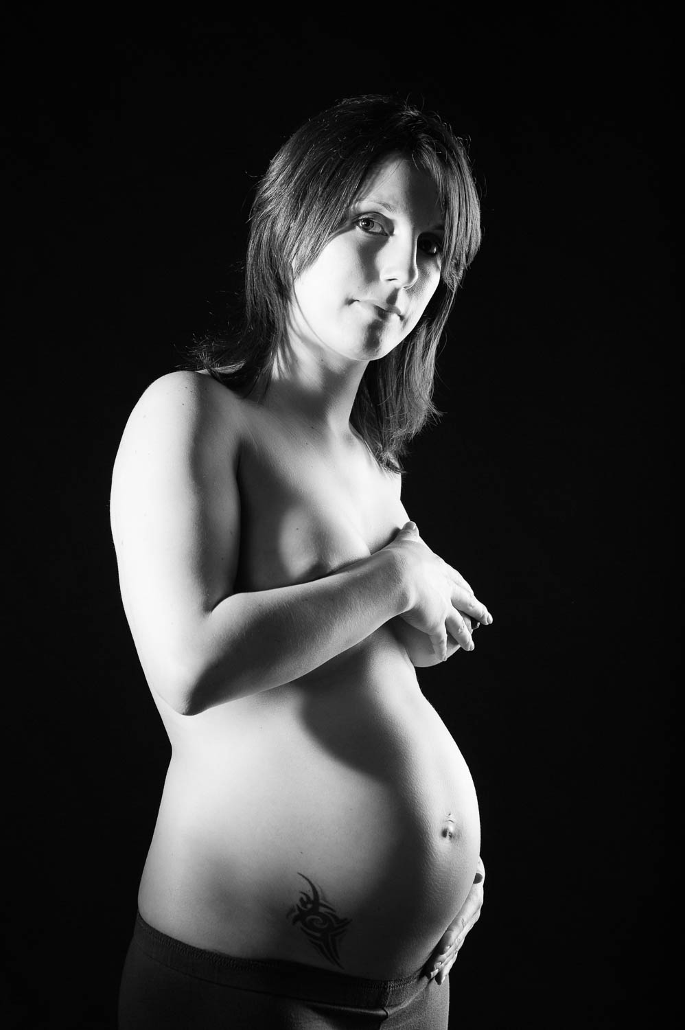  portrait noir et blanc d'une femme enceinte sur fond noir en studio 