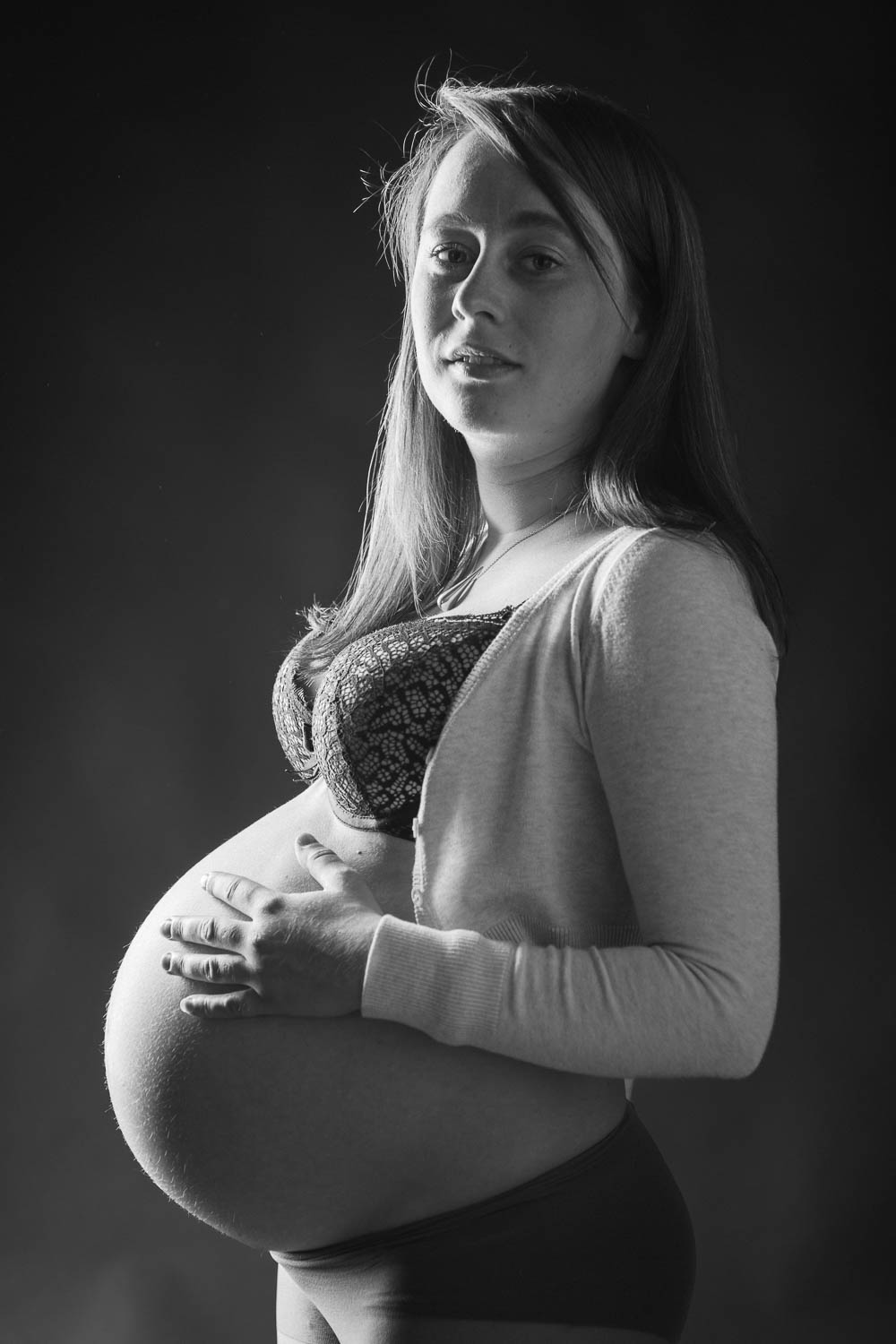  portrait noir et blanc d'une femme enceinte sur fond noir en studio 