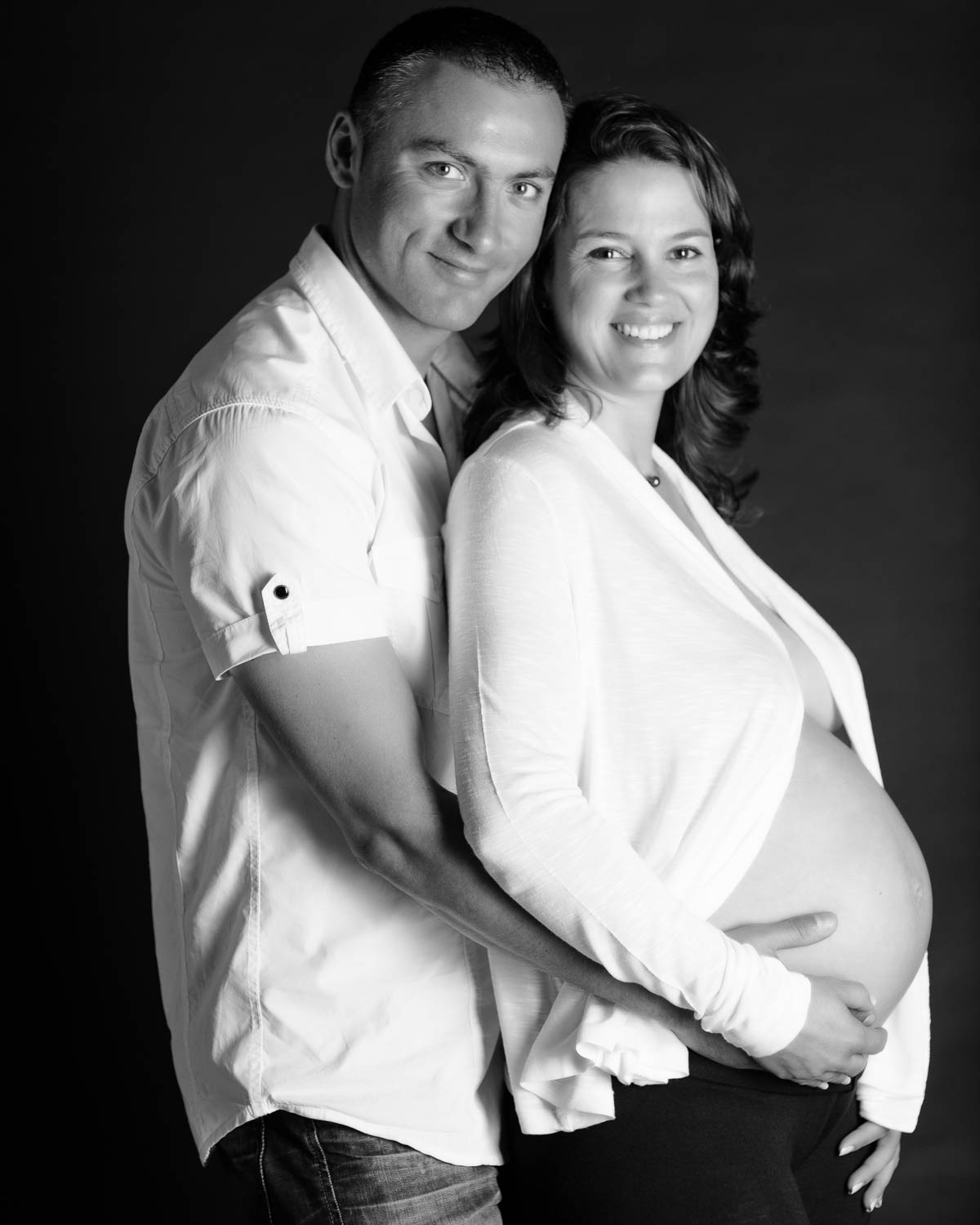  portrait noir et blanc maternité de couple sur fond noir en studio 